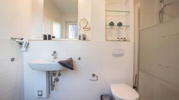 Ein modernes Badezimmer mit Waschbecken, Spiegel, Toilette und Dusche.