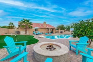 A backyard with a swimming pool, a fire pit, and outdoor seating.