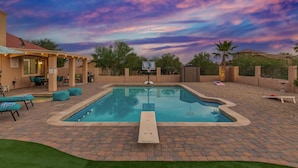 Un patio trasero con piscina, muebles de patio y aro de baloncesto.