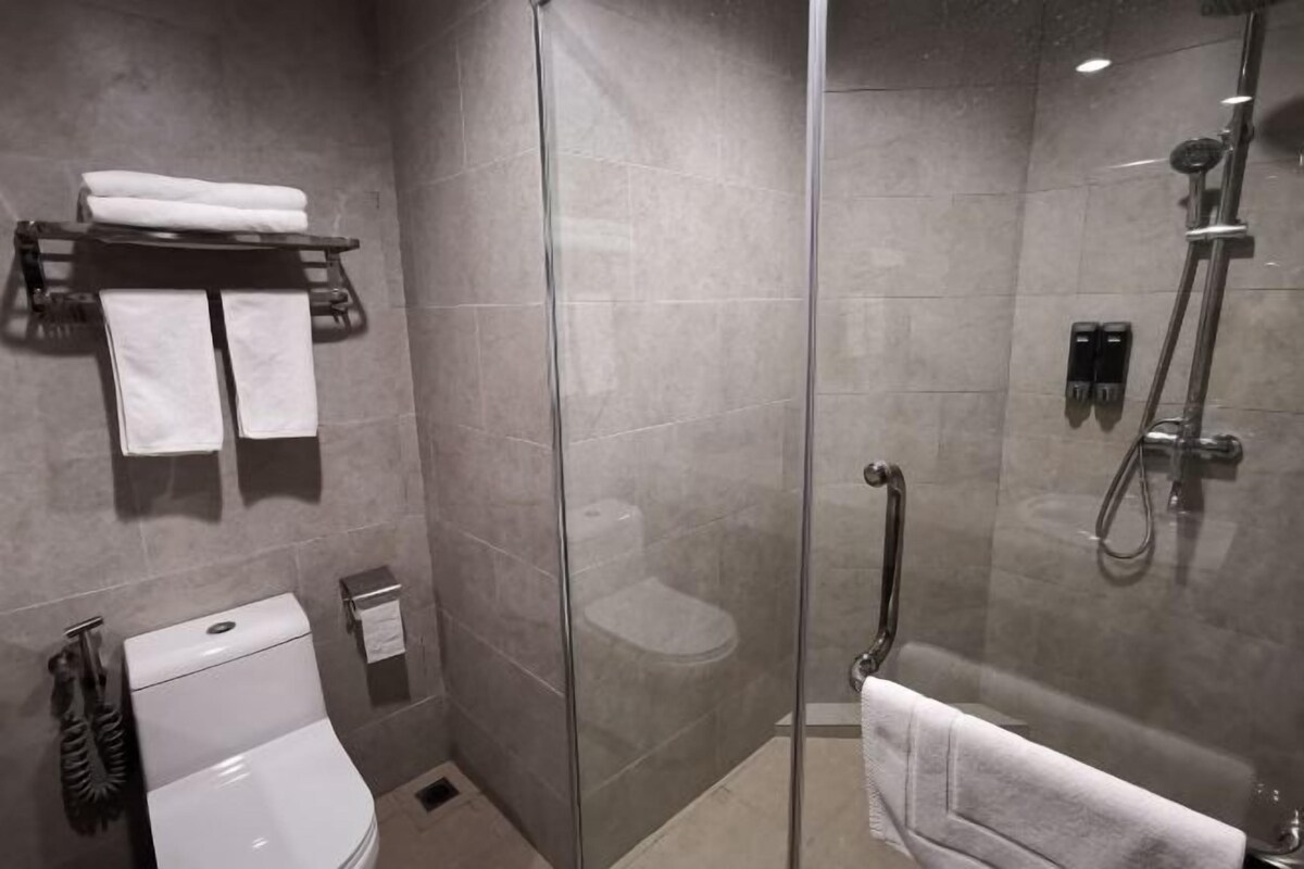 A modern bathroom with a glass-enclosed shower, a toilet, and a bathtub.
