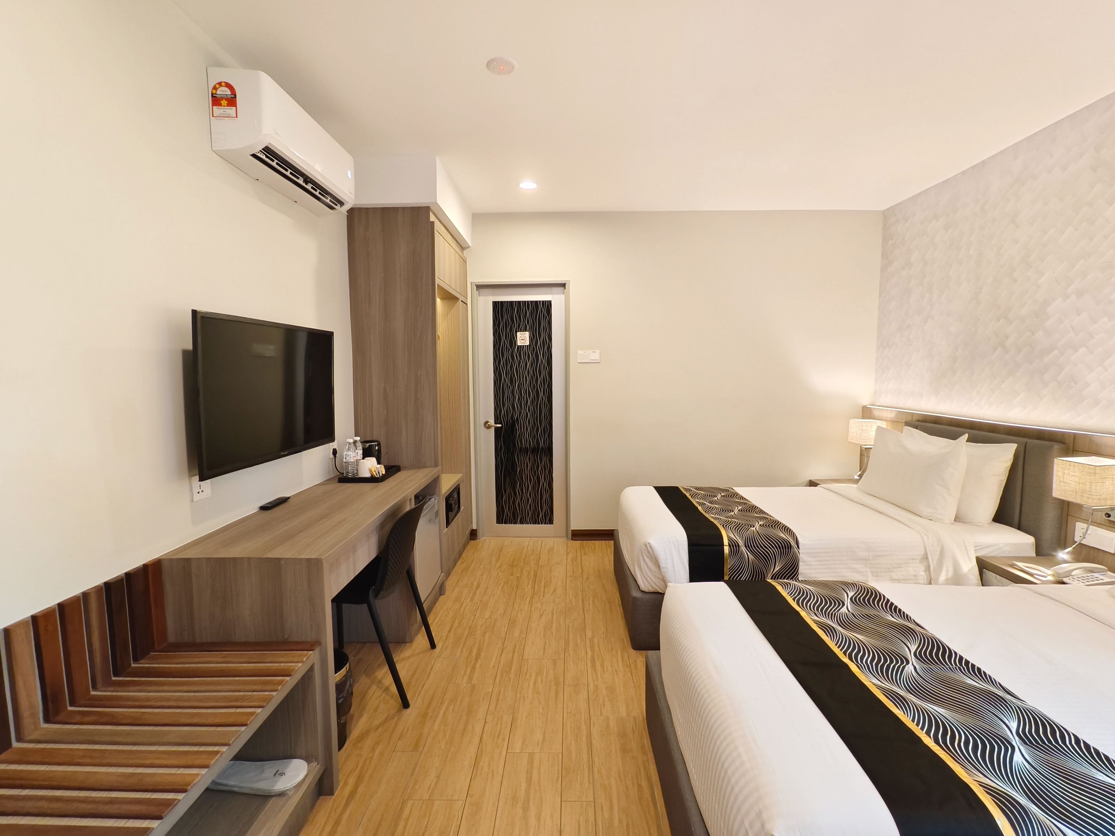 A hotel room with a TV, desk, chair, bed, and a staircase.