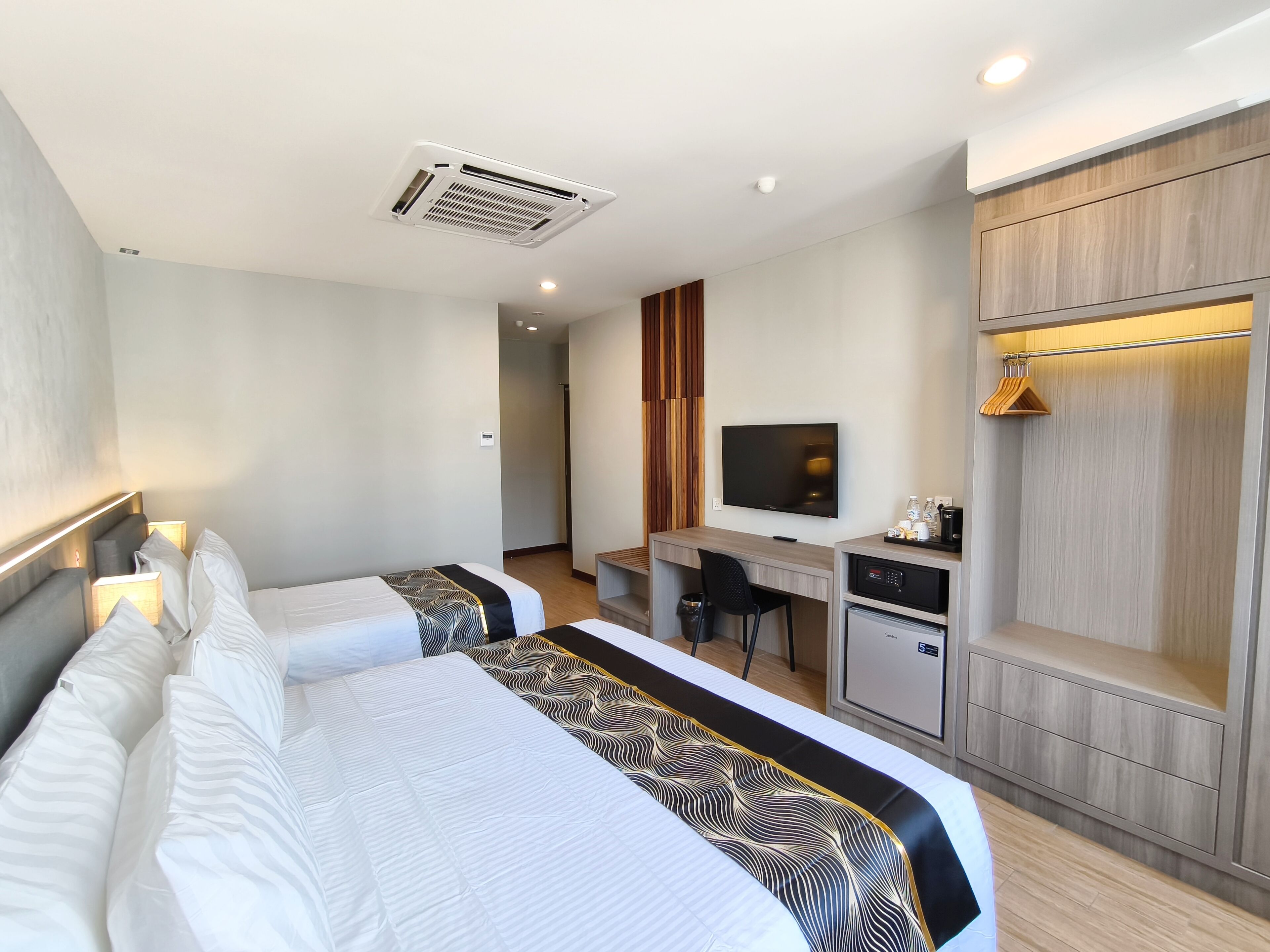 Une chambre d’hôtel avec deux lits, un bureau, une télévision et un mini-bar.