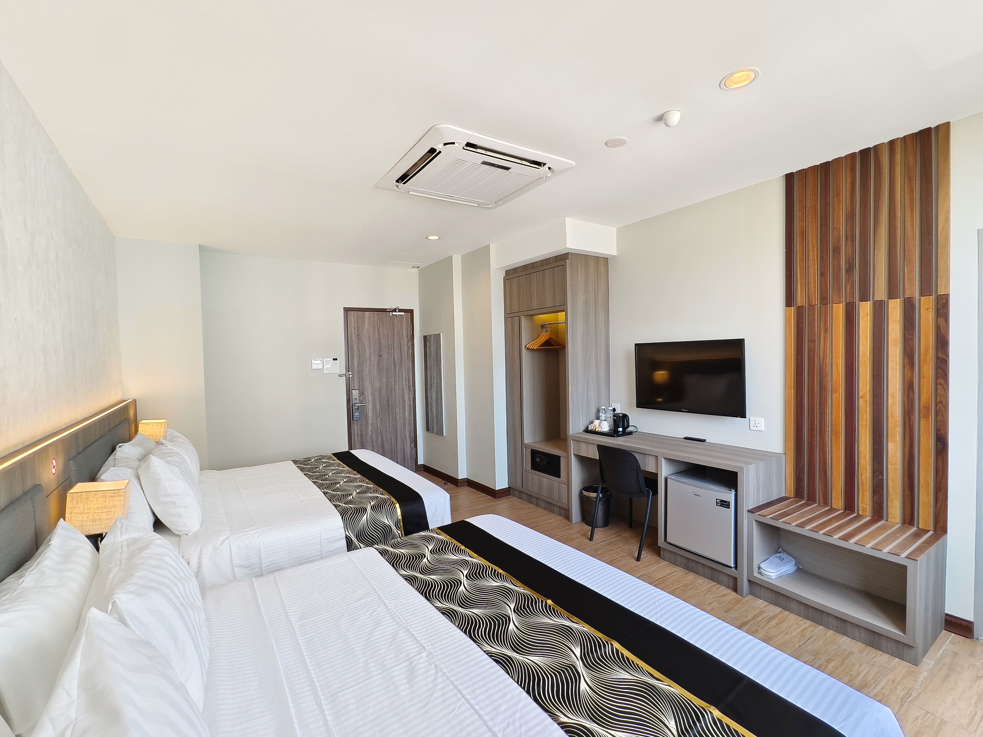 Una habitación de hotel con dos camas, un escritorio, un televisor y un armario.