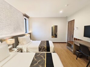 A hotel room with two beds, a desk, a TV, and a mirror. - Veno Hotel (George Town)