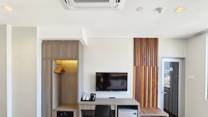 A modern hotel room with a desk, chair, TV, mini-fridge, and a built-in wardrobe. - Veno Hotel (George Town)