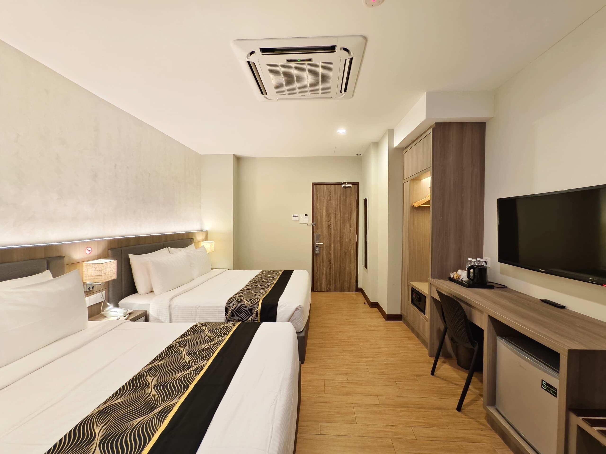 A hotel room with two beds, a desk, a television, and a wardrobe.
