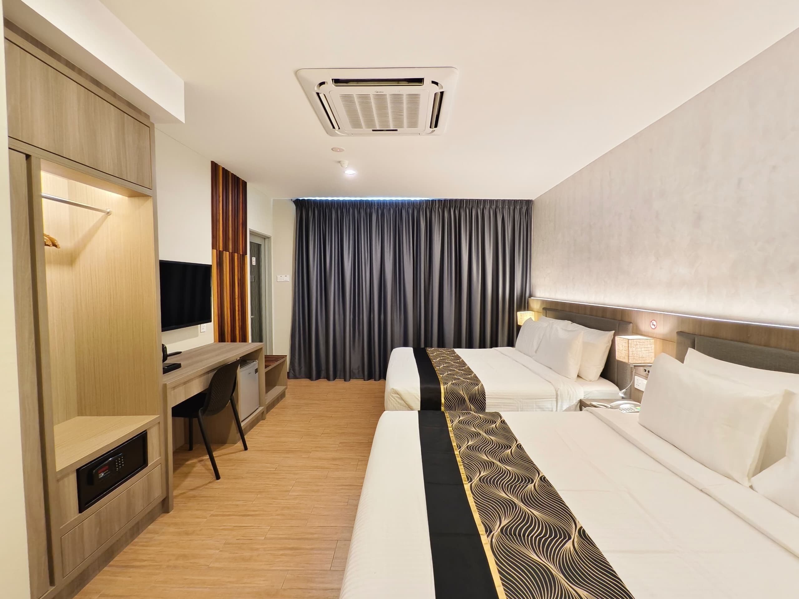 A hotel room with a bed, a desk, a TV, a wardrobe, and a curtain.