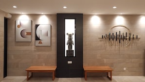 A modern lobby with two wooden benches, a black vertical display, and abstract wall art. - Veno Hotel (George Town)