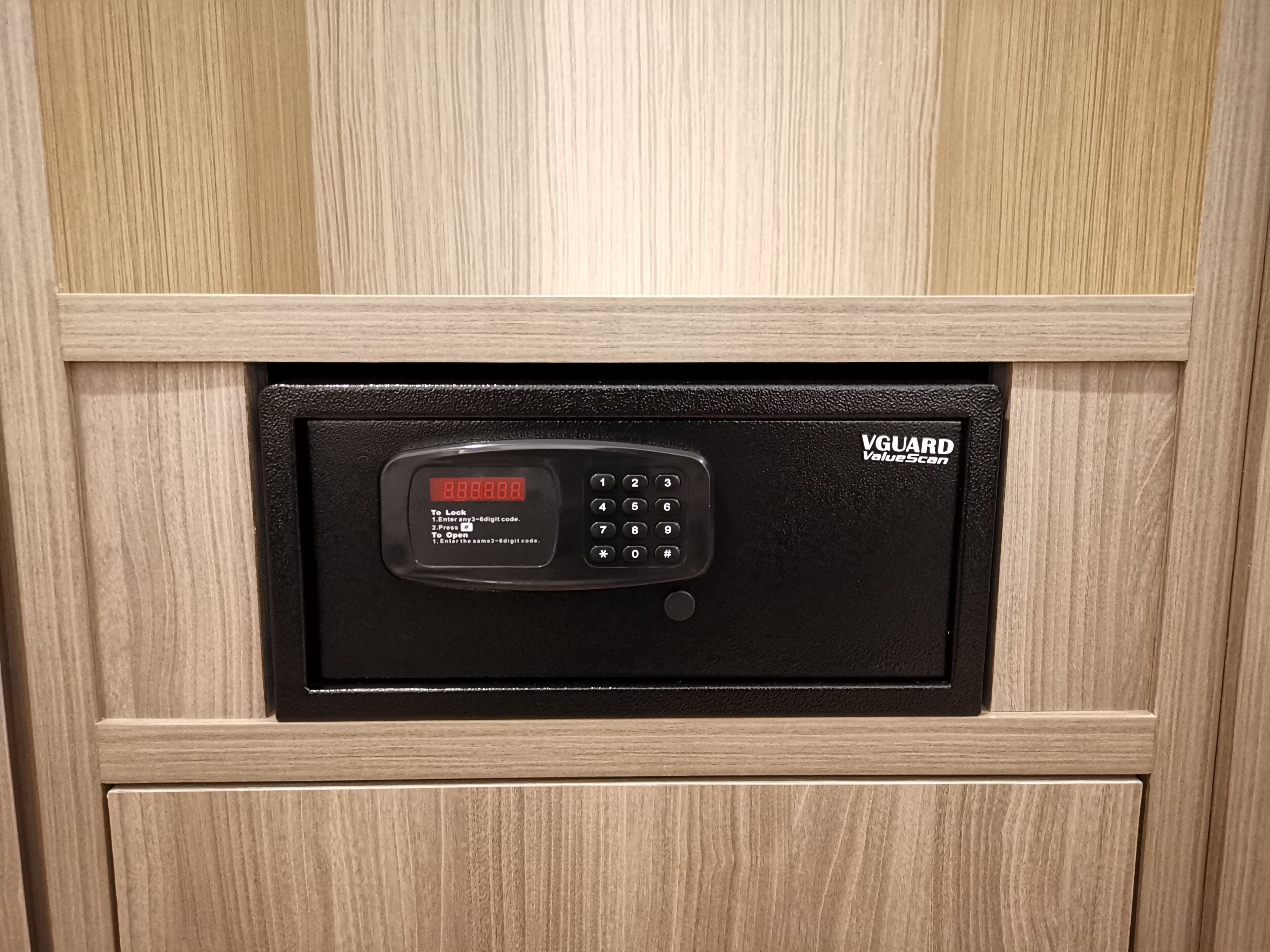 A black electronic keypad with a digital display, labeled "VGUARD ValueScan," mounted on a wooden panel.