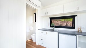 Una cocina moderna con armarios blancos, una ventana con marco negro y lavavajillas integrado.