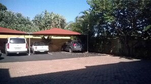 Guests can park their vehicles under a covered structure surrounded by trees.