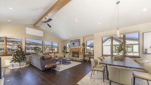 A spacious living area with a fireplace, a dining table, and a Christmas tree. - Modern Elegance, Stunning Mountain Views, Hot Tub, Fire Pit, Walk to River! (Breckenridge)