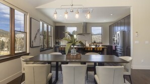 A modern kitchen with a dining area, large windows, and a view of the outdoors. - Modern Elegance, Stunning Mountain Views, Hot Tub, Fire Pit, Walk to River! (Breckenridge)