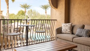 A balcony with a wicker sofa, two metal chairs, a small table, and a view of a swimming pool. - Eucalyptus by AvantStay | Stunning Scottsdale Home w/ Communal Pool & Hot Tub (Scottsdale)
