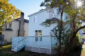 A two-story house with a white exterior, a brick chimney, and a blue staircase leading to a deck. - Elizabeth Rd House by Palmetto Vacations (Myrtle Beach)