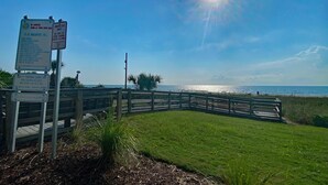 A wooden boardwalk leading to a beach with a sign indicating no umbrellas or sharing devices allowed. - Camelot by the Sea by Palmetto Vacations (Myrtle Beach)