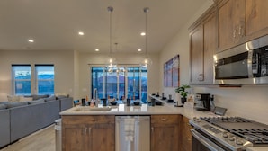 A modern kitchen with a central island, stainless steel appliances, and a view to the outside. - Snow Canyon Oasis, Ocotillo 42, Large Private Pool and Hot Tub, 2 Firepits, 2 PlayStations (Santa Clara)