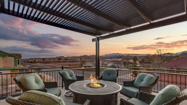 A patio with wicker furniture and a central fire feature, overlooking a scenic landscape. - Snow Canyon Oasis, Ocotillo 42, Large Private Pool and Hot Tub, 2 Firepits, 2 PlayStations (Santa Clara)