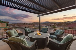 Un patio con mobili in vimini e un elemento centrale a camino, con vista su un paesaggio panoramico.