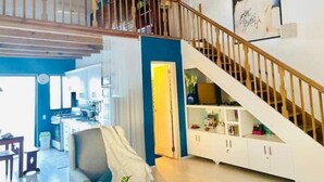 Un amplio salón con una escalera que sube a un segundo piso, una cocina y un comedor.