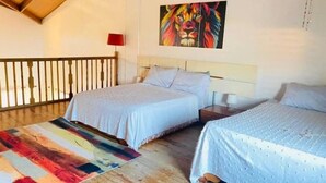 Un dormitorio con dos camas, un tapete colorido y un cuadro de un león en la pared.