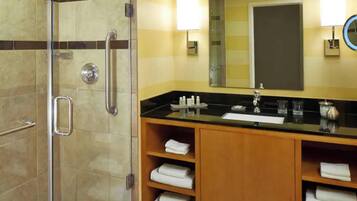 A bathroom with a glass-enclosed shower, a sink with a vanity, and a mirror.