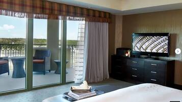 Une chambre d’hôtel avec un balcon, une télévision, un lit et un bureau avec une chaise.