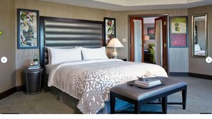 A hotel room with a large bed, a bedside table with a lamp, a small round table with a book, and a bench. - St. Augustine Villa for 6 Golf courses, tons of amenities & close to attractions (St. Augustine)