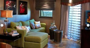 A green sofa with multiple cushions, a small side table with a lamp, and a decorative item on a side table.