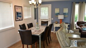 A dining area with a wooden table and chairs, a chandelier, and artwork on the walls.