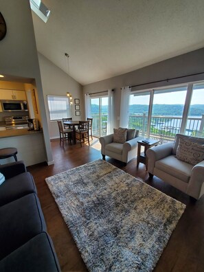 A spacious living area with a large rug, two sofas, a dining table with chairs, and a kitchen in the background. - Treehouse Condos - Branson (Branson)