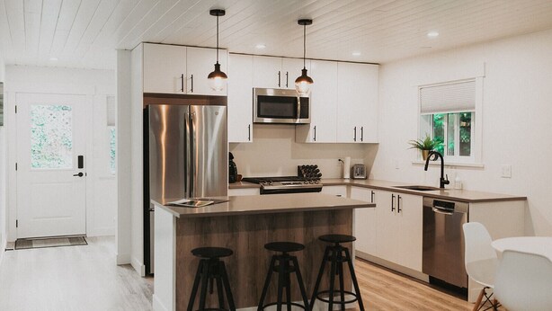 A modern kitchen with a central island, stainless steel appliances, and bar stools.