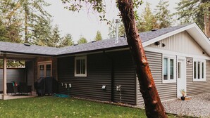 A two-story house with a covered patio and a tree in the foreground.