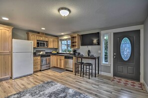 Una cocina moderna con armarios de madera, electrodomésticos de acero inoxidable y una puerta negra con un ventanal de vitral.