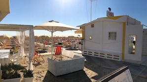 Eine Dachterrasse mit Liegestühlen, Sonnenschirmen und einer kleinen Sitzecke.