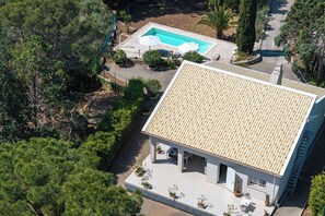 Ein Haus mit Ziegeldach, Schwimmbad und Garten mit Bäumen und Sträuchern.