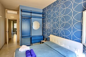 Experience a minimalist retreat with a neatly made bed, stylish wardrobe, and geometric patterned wall.