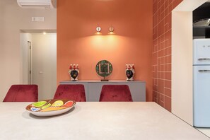 A dining area with a table, chairs, and a refrigerator.