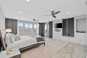 Relax in a spacious room with a large bed, flat-screen TV, and ceiling fans for a comfortable stay.