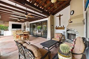 Un espace extérieur aménagé en terrasse, avec des meubles en bois, une cheminée en pierre et un cactus.