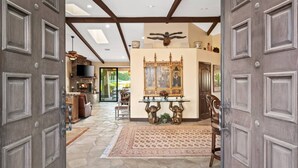 A spacious interior with a stone floor, a fireplace, a television, and a dining area with a table and chairs.
