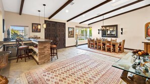A spacious kitchen with a stone island, wooden chairs, and a dining area with a patterned rug.