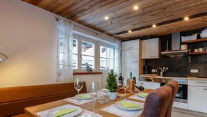 A dining area with a wooden table set for two, a small potted plant, and wine glasses. - Atmospheric ski-in/ski-out with terrace (Rauris)