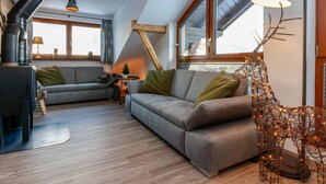A cozy loft-style living room with a fireplace, two sofas, a coffee table, and a decorative reindeer sculpture. - Atmospheric ski-in/ski-out with terrace (Rauris)