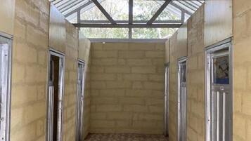 A corridor with a tiled floor, metal doors, and a corrugated metal roof.