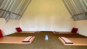 A spacious room with a high ceiling and metal beams, featuring two exercise mats and a pair of water bottles on the floor. - Supercamp Sakura Hills (Tawangmangu)