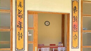 A room with a wooden door, a clock on the wall, and a table with chairs. - Supercamp Sakura Hills (Tawangmangu)