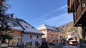 A narrow street with snow-covered ground, traditional buildings with wooden facades, and a visible bookstore. - Superb Duplex 8/10 pers 5ch 3sdb 1 balcony 150M2 cocooning in the heart of Queyras (Aiguilles)