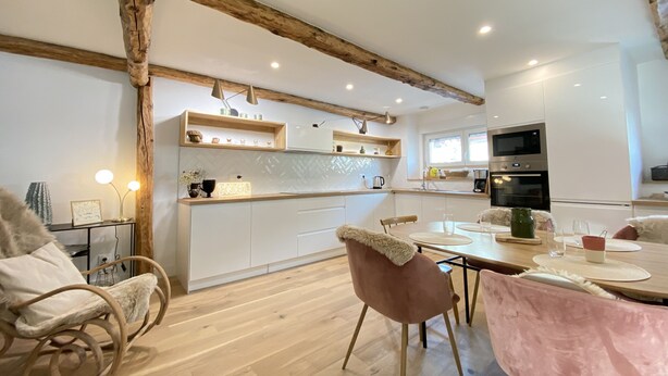 A modern kitchen with white cabinets, wooden beams, and a herringbone tile backsplash. - Superb Duplex 8/10 pers 5ch 3sdb 1 balcony 150M2 cocooning in the heart of Queyras (Aiguilles)