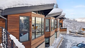 Een modern houten gebouw met grote ramen en een sneeuwbedekt, schuin dak.